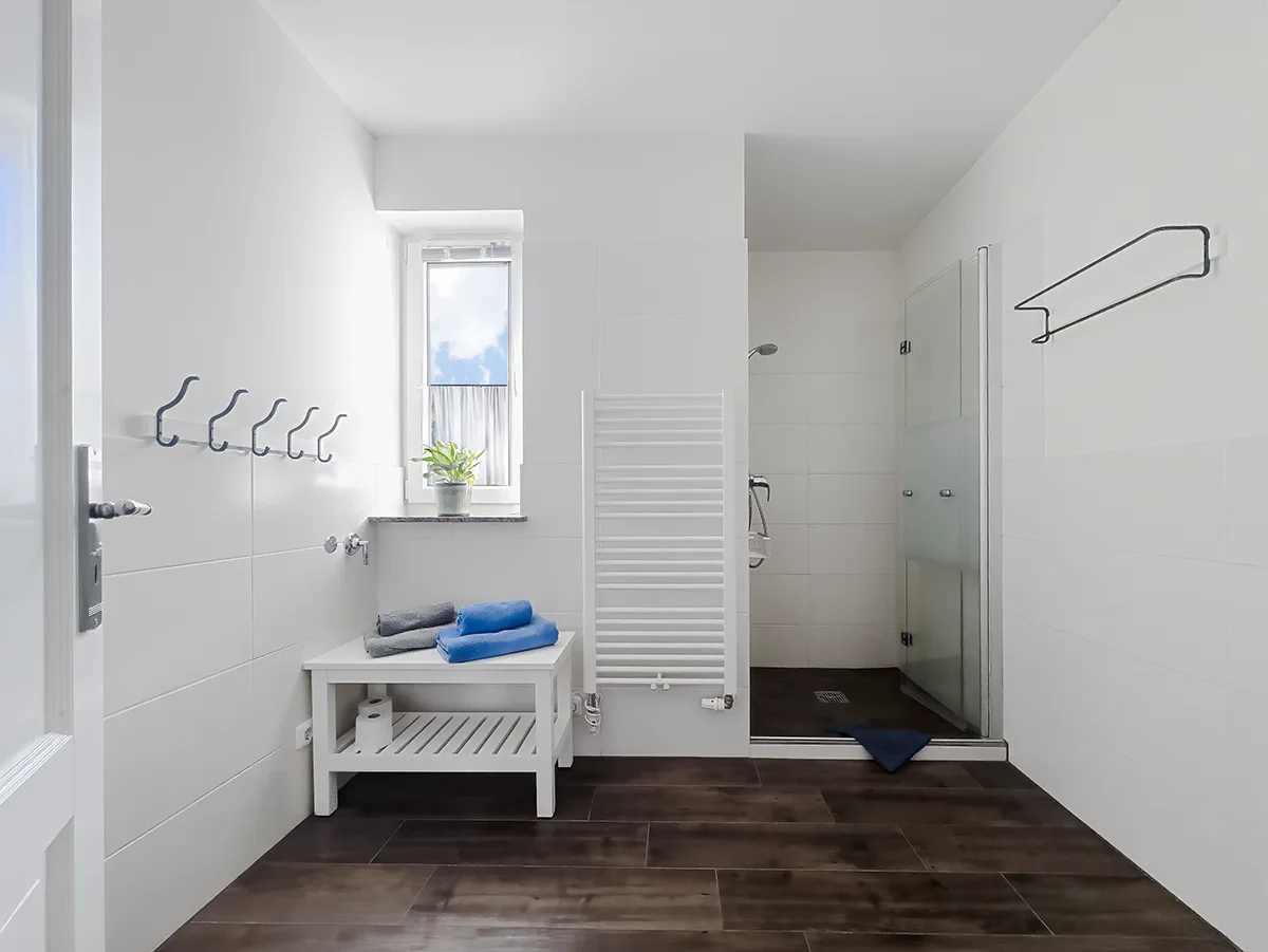 Barrierearmes Badezimmer der Ferienwohnung 4 mit bodengleicher Dusche, weißem Badmöbel und Handtuchtrockner.