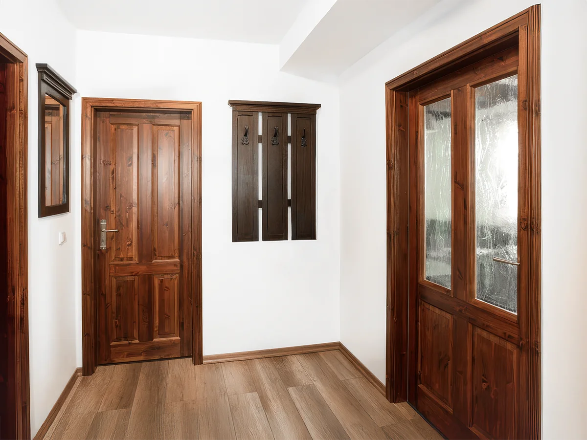 Flur der Ferienwohnung 3 mit dunklen Echtholztüren, Garderobe und hochwertigem Laminatfußboden.