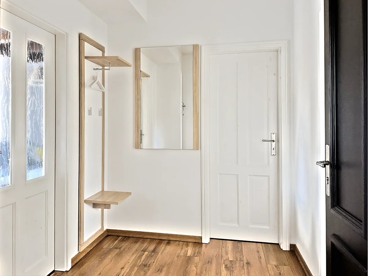 Eingangsbereich der Ferienwohnung 4 mit moderner Wandgarderobe, großem Spiegel und hellen Wänden.