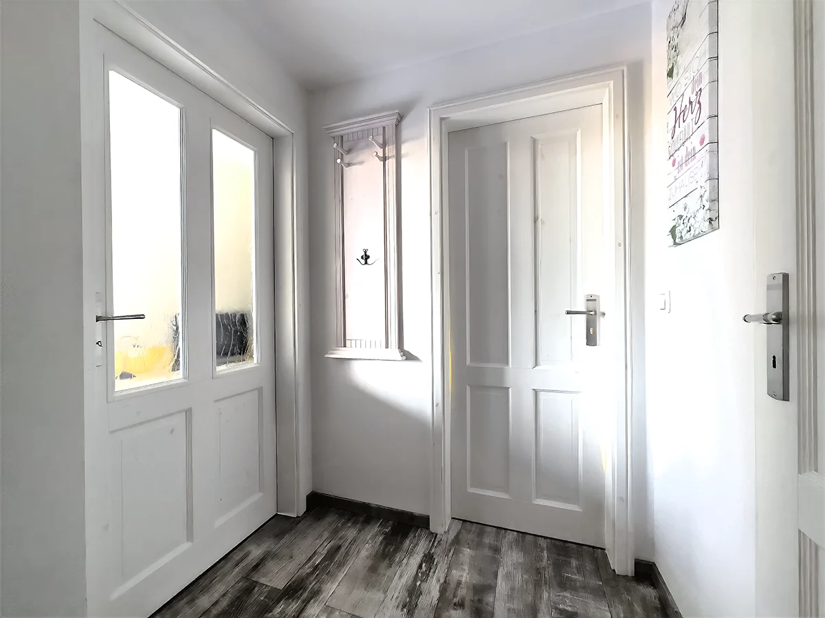 Heller Flur der Ferienwohnung 6 in Markkleeberg mit weißen Kassettentüren, moderner Garderobe und dunklem Laminatboden