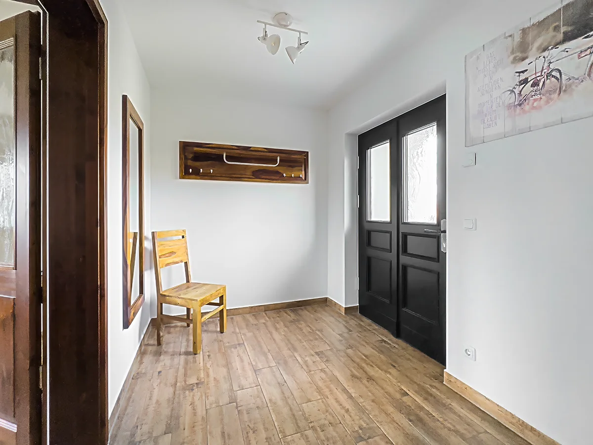 Heller Flur der Ferienwohnung 7 mit eleganten weißen Kassettentüren, hölzernem Bodenbelag und dekorativer Wandgarderobe