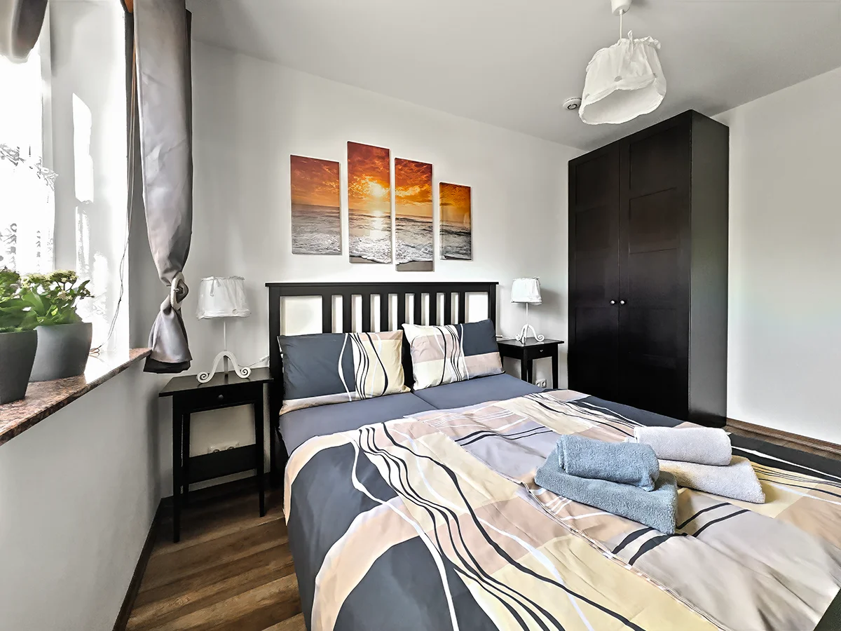 Schlafzimmer der Ferienwohnung 1 mit Doppelbett, dunklem Kleiderschrank und bereitliegenden Handtüchern im Ferienhaus Kaiserhof.