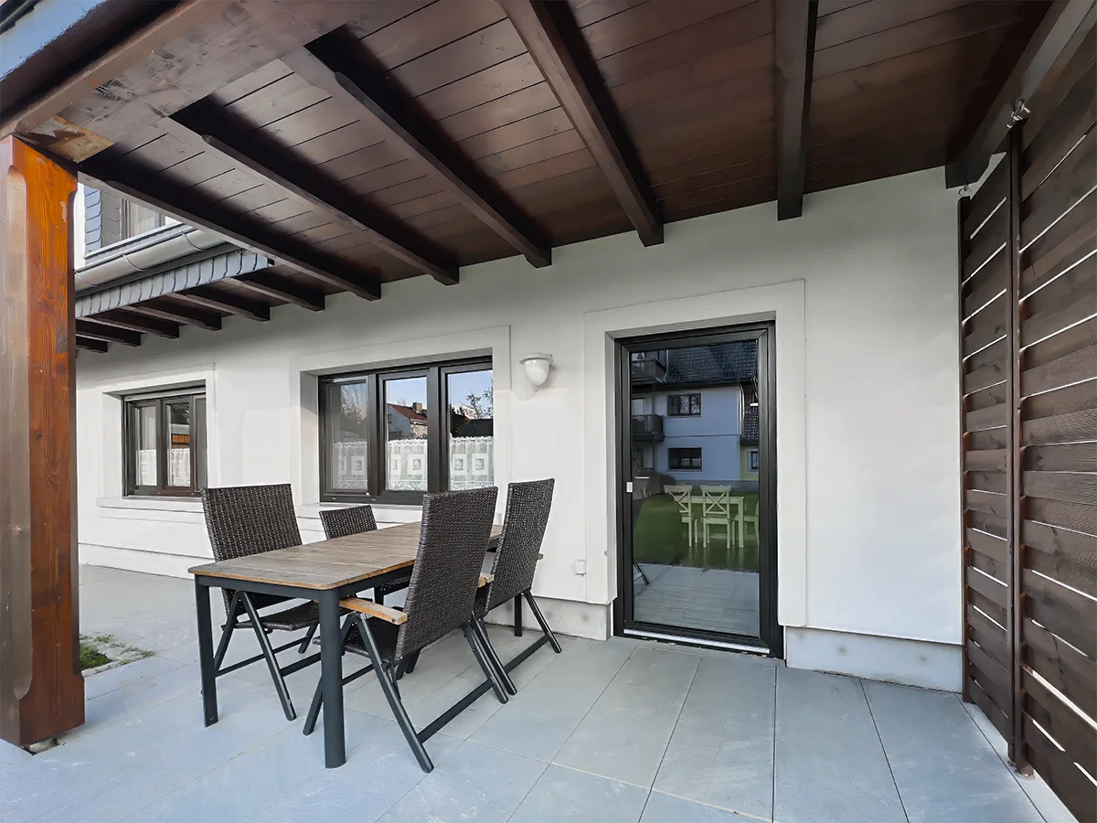 Überdachte Terrasse der Ferienwohnung 8 mit anthrazitfarbener Sitzgruppe und direktem Zugang zum Garten des Kaiserhofs.