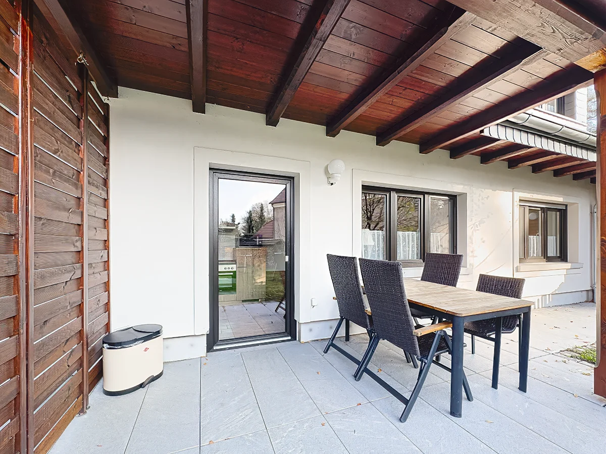 Sonniger Terrasse der Ferienwohnung 7 mit Sitzgruppe, großem Sonnenschirm und weitem Blick ins Grüne
