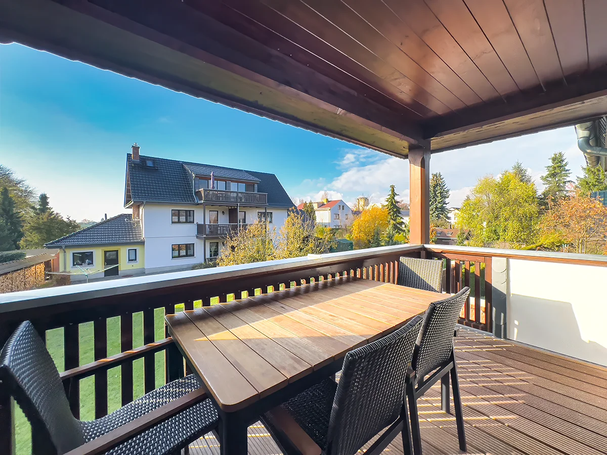 Große Dachterrasse der Ferienwohnung 9/10 mit Holzboden, massivem Gartentisch und Blick auf die Nachbarschaft in Markkleeberg.