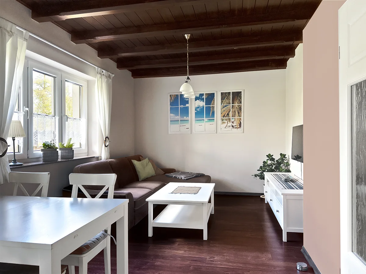 Helles Wohnzimmer der Ferienwohnung 2 in Markkleeberg mit weißem Couchtisch, dunklem Sofa und moderner Wanddekoration