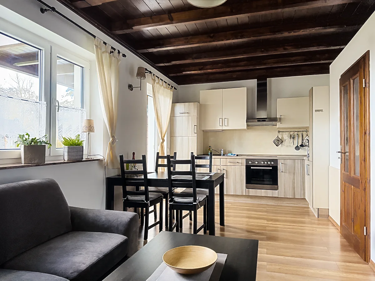 Offener Wohn- und Essbereich der Ferienwohnung 3 in Markkleeberg mit moderner Einbauküche und rustikaler Holzbalkendecke