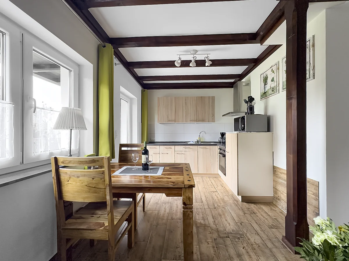 Alternativer Text: Moderne Einbauküche der Ferienwohnung 7 in Markkleeberg mit grauen Fronten, gelber Akzentwand und hellem Essbereich